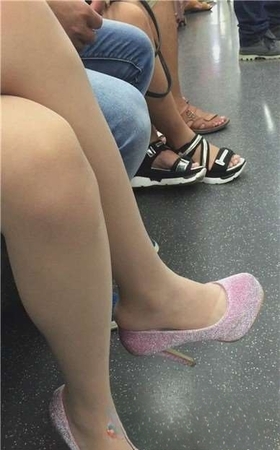 地铁上低头玩手机的女孩，一双高跟很抢眼。