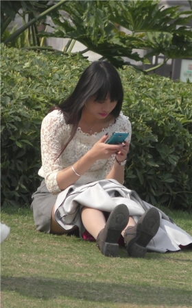 草地上玩手机的美女