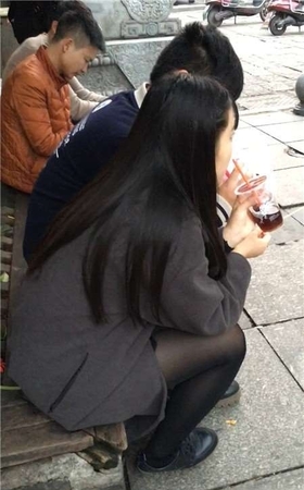 蹲路边喝饮料的黑丝袜美腿青春妹子