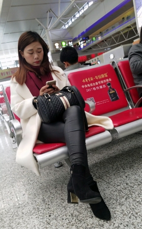 高铁站候车的黑色紧身皮裤长发少妇