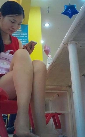 边玩手机边挑些等孩子玩蹦蹦床的红衣少f