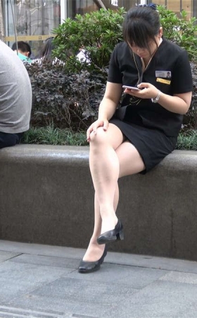 花圃边玩手机的制服街拍美女