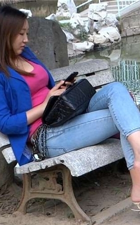 丰满紧身蓝牛高跟鞋美女公园石凳上玩手机